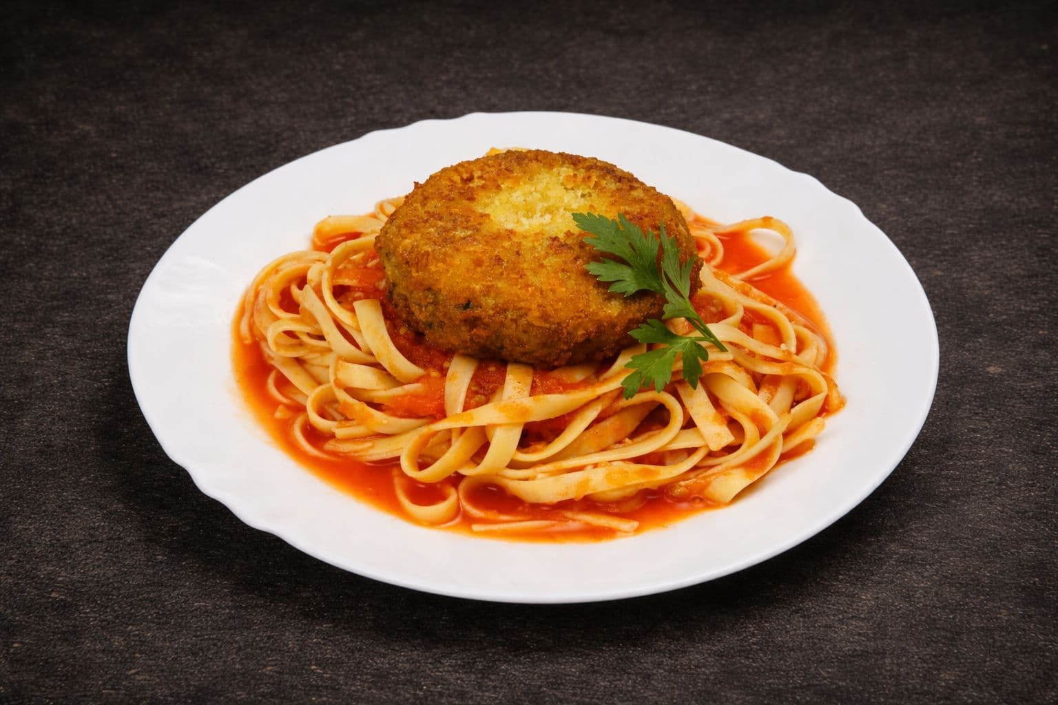 Fettucine servido com polpetone recheado de queijo e molho por cima.